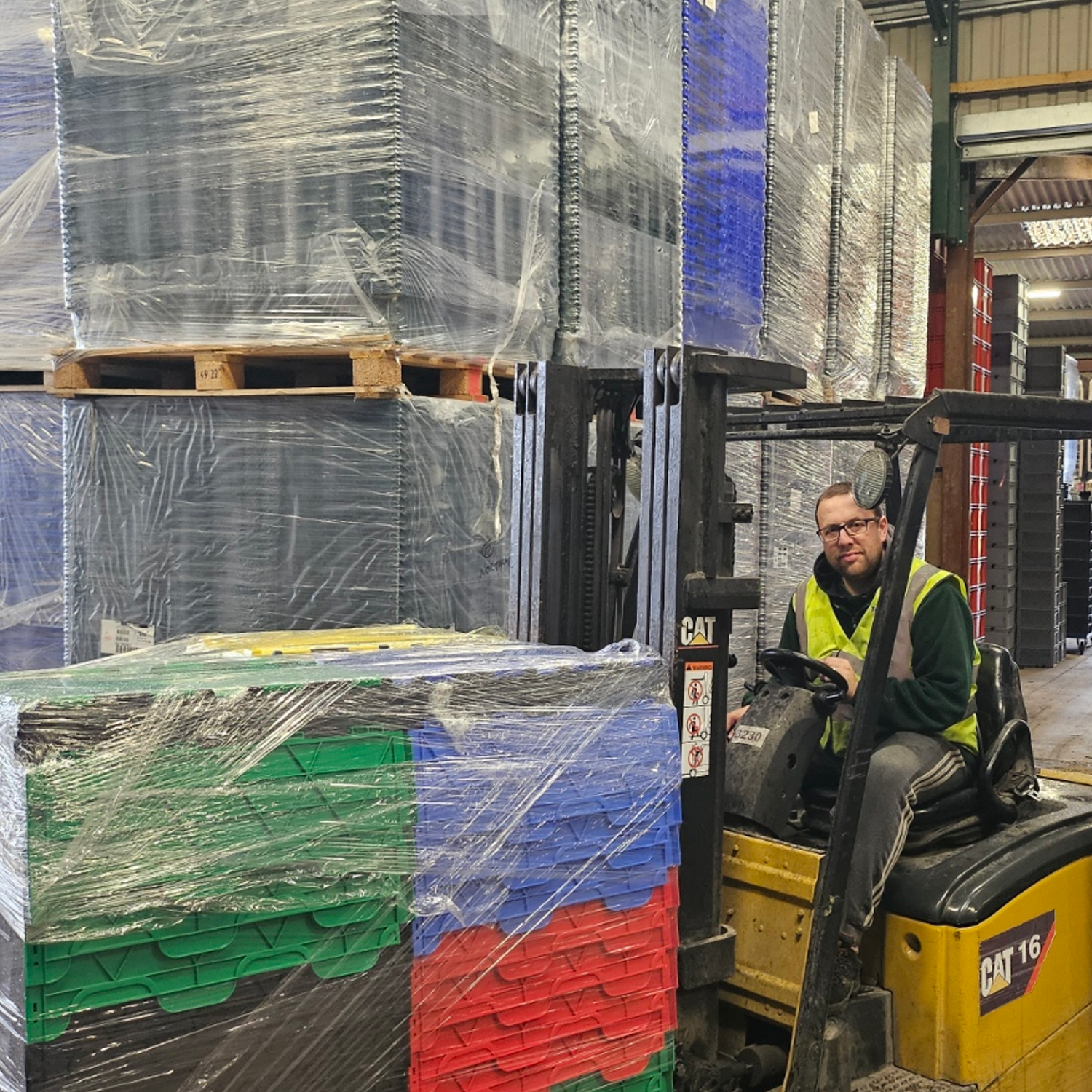 Warehouse manager Joe operating a forklift with pallets of wrapped goods in a warehouse.