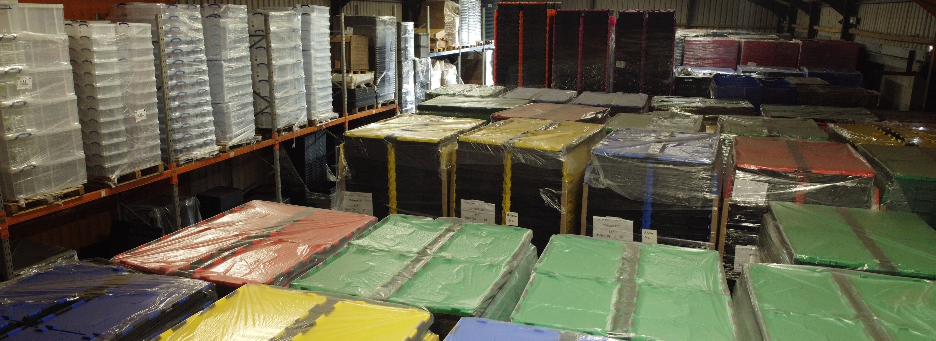 Storage room with stacked boxes and crates on shelves and the floor.